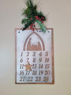 a wooden clock hanging from the side of a wall next to a christmas tree branch