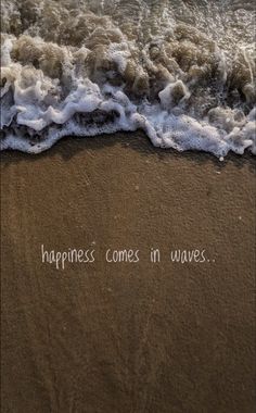 the words happiness comes in waves written on the sand at the ocean's edge