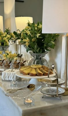 a table topped with cakes and flowers on top of a white table cloth next to two lamps