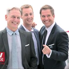 three men in suits and ties posing for the camera with one pointing at the camera