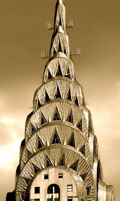 a very tall building that has a clock on it's face and is surrounded by clouds