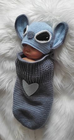 a baby wearing a knitted hat and sleeping bag on top of a fluffy white blanket