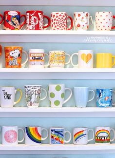 many different colored coffee mugs are on the shelves