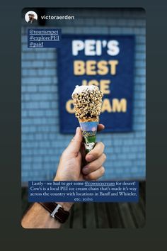 a person holding an ice cream cone in front of a blue brick wall with the words pet's best ice cream on it