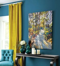 a room with blue walls, yellow curtains and a painting on the wall above a console table