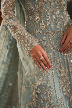 a woman in a blue dress is holding onto her wedding ring