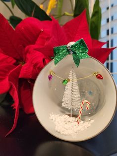 a glass ornament with a christmas tree on it and candy canes in the bowl