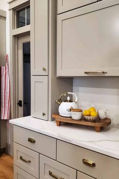 a kitchen with white cabinets and wooden trays on the counter top next to an oven