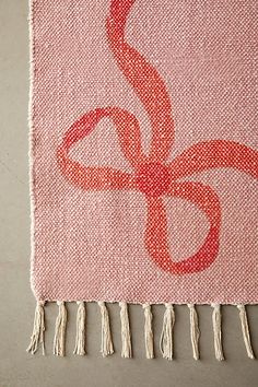 a red and white wall hanging with tassels on top of it's side