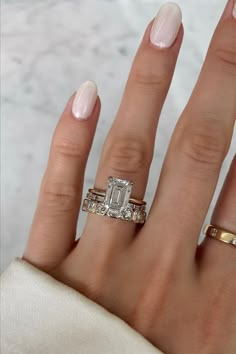 a woman's hand with two gold rings and a diamond ring on her finger