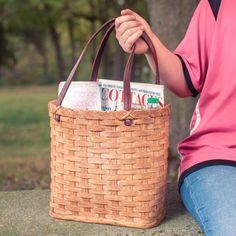 a person sitting on the ground holding a basket with magazines in it