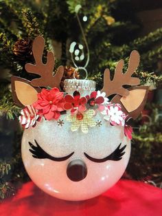 a christmas ornament with reindeer antlers and flowers on it's head