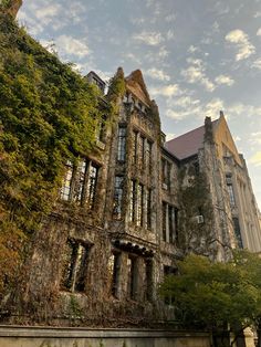 an old building with ivy growing on it's sides and trees in the foreground