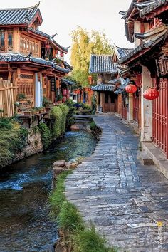 a river running through a small town with red lanterns hanging from it's roof