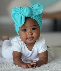 a baby wearing a blue headband laying on top of a bed