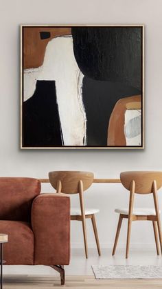 a living room with two chairs and a painting hanging on the wall above it's coffee table