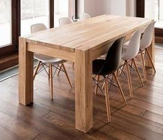 a wooden table with chairs around it in the middle of a room next to large windows