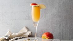 a glass filled with orange juice next to an apple and nuts on a marble table