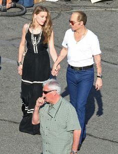 a woman walking down the street holding hands with an older man in front of her