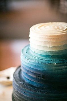 a multi layer cake with white frosting and blue icing on it's top