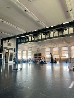 people are sitting on the floor in an empty room with metal railings and windows