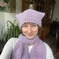 a woman wearing a purple knitted hat and scarf with a cat earflap