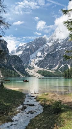 there is a small boat on the water in the mountain lake with rocks and grass