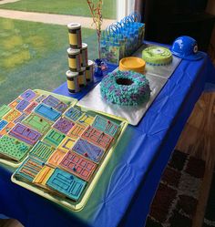 a table topped with cakes and other items on top of a blue cloth covered table