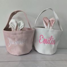 two small baskets with bunny ears and name on the front, one is pink and white