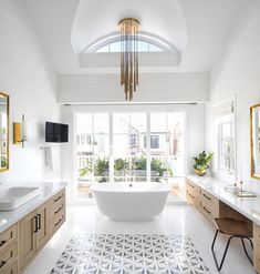 a large white bath tub sitting in a bathroom next to two sinks and a mirror