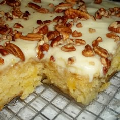 a cake with white frosting and pecans on top sitting on a cooling rack