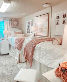 two beds in a room with white furniture and pink flowers on the nightstands next to them