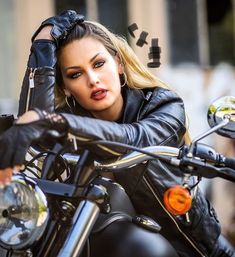 a woman sitting on top of a motorcycle with her hand on the handlebars