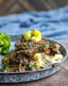 a plate full of food with broccoli and meat on it, next to a fork