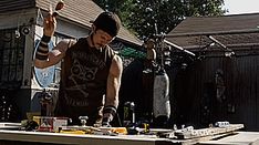 a man standing in front of a wooden table with various items on top of it