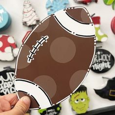 a hand holding up a football shaped sticker in front of many other magnets