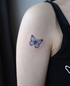 a woman's arm with a butterfly tattoo on the left side of her shoulder