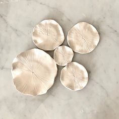 four silver plates sitting on top of a marble counter