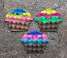 three small cupcakes made out of perler beads on top of a rock