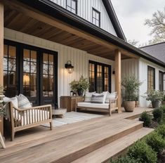 a porch with wooden steps leading up to the front door and patio furniture on it