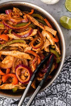 a skillet filled with chicken, peppers and onions