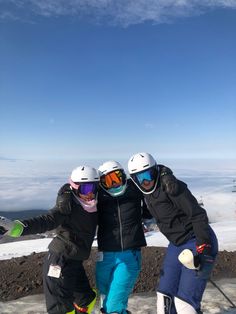 three skiers pose for a photo on top of a mountain