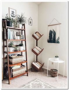 a living room filled with lots of plants and bookshelves next to a white table