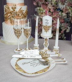 a table topped with white and gold wedding cake next to wine glasses filled with champagne