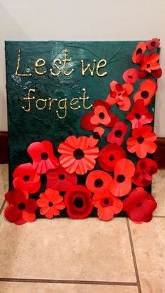 a sign that says let we forget with red poppies in the center and words written on it