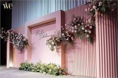 a pink wall with flowers and greenery on it