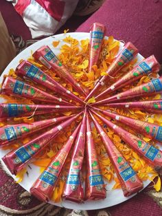 a white plate topped with lots of pink and orange candy tubes covered in gold leaves