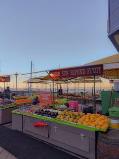 an outdoor fruit stand with oranges, lemons and other fruits for sale at sunset