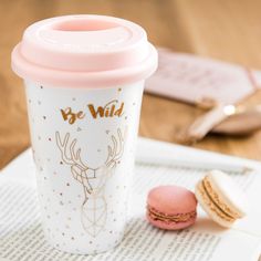 a pink cup sitting on top of a table next to a macaroni and cheese