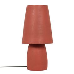 a red lamp with a black cord attached to it on a white wall behind the lamp